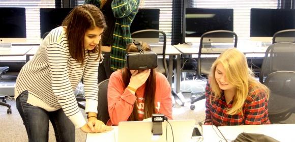 Three first-year SJMC students in the Multimedia Lab; the student in the center is wearing a virtual reality headset.